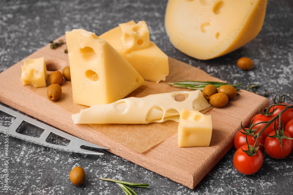 Board with pieces of Swiss cheese and olives on grey background