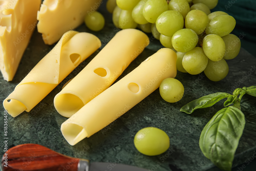 Slices of tasty Swiss cheese and grapes on table