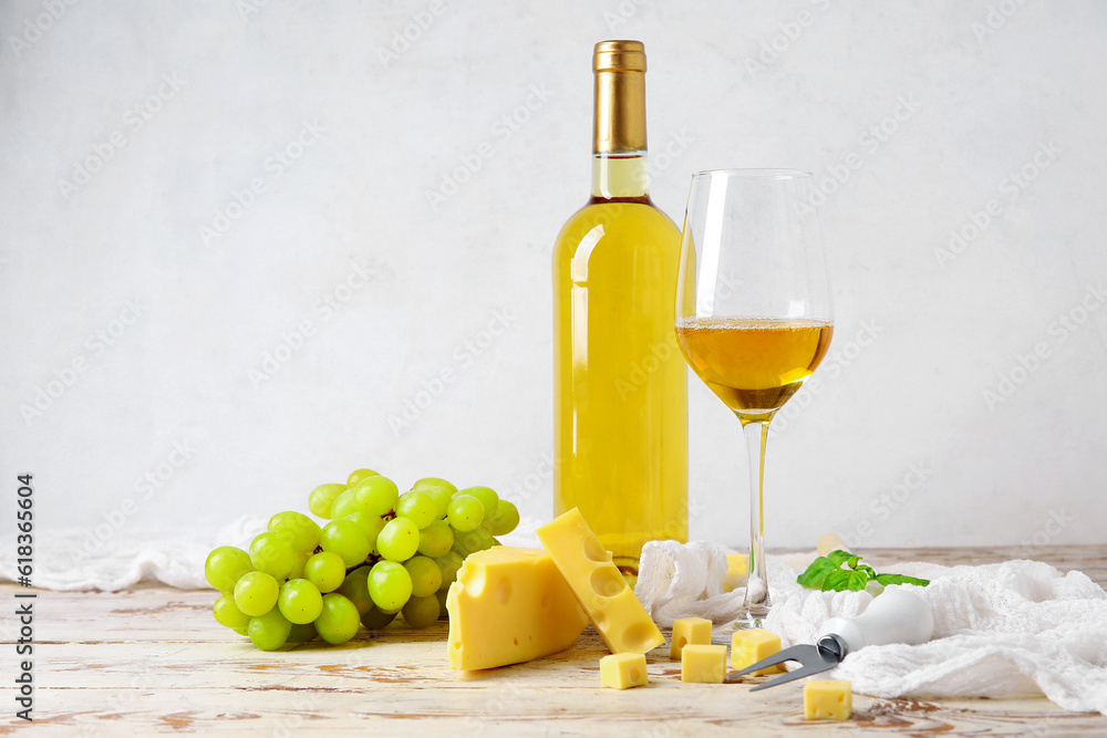 Tasty Swiss cheese, grapes, bottle and glass of wine on table