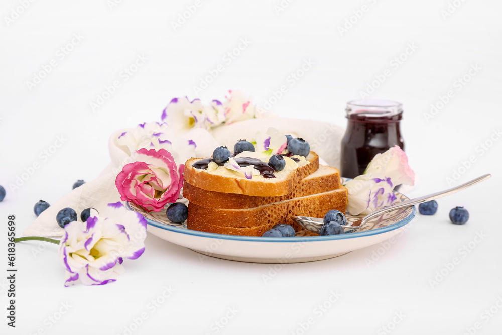 Plate with delicious jam toasts, blueberries and flowers on white background