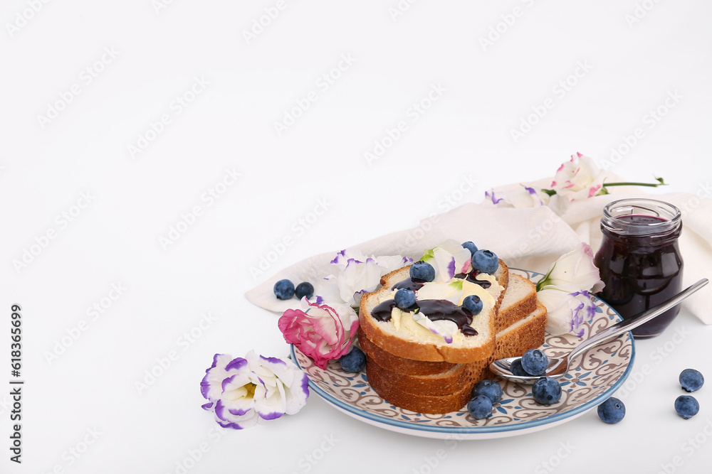 Plate with delicious jam toasts, blueberries and flowers on white background