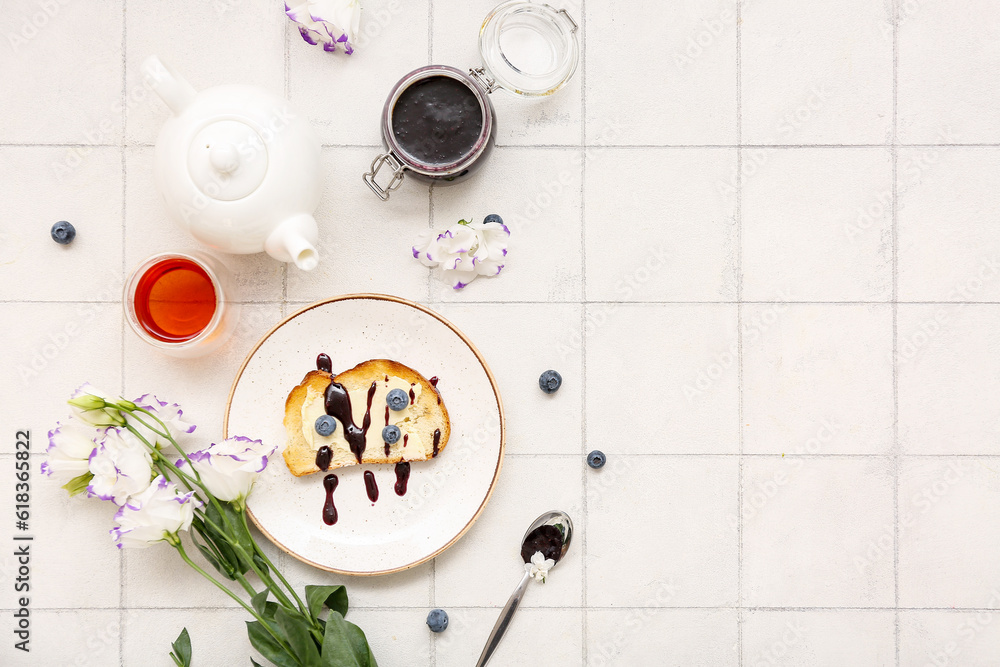 Plate with sweet jam toast, blueberries and glass of tea on white tiled table