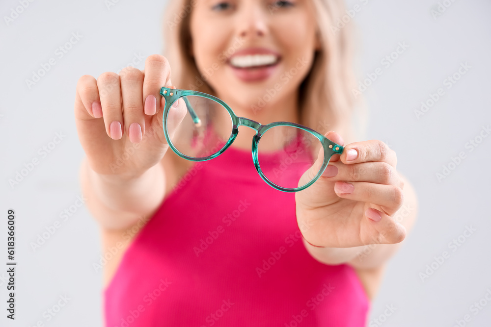 Young woman in stylish eyeglasses on light background, closeup