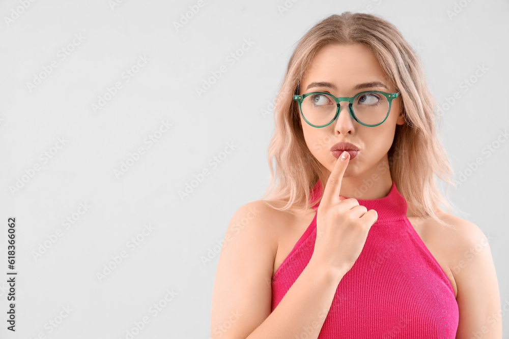 Thoughtful young woman in stylish eyeglasses on light background, closeup