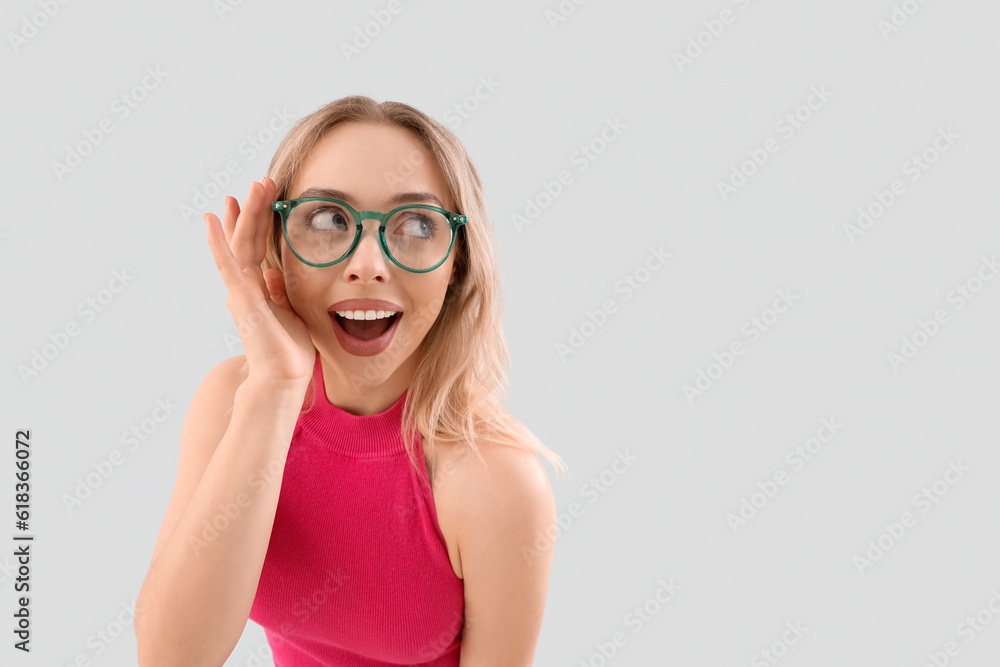 Happy young woman in stylish eyeglasses on light background