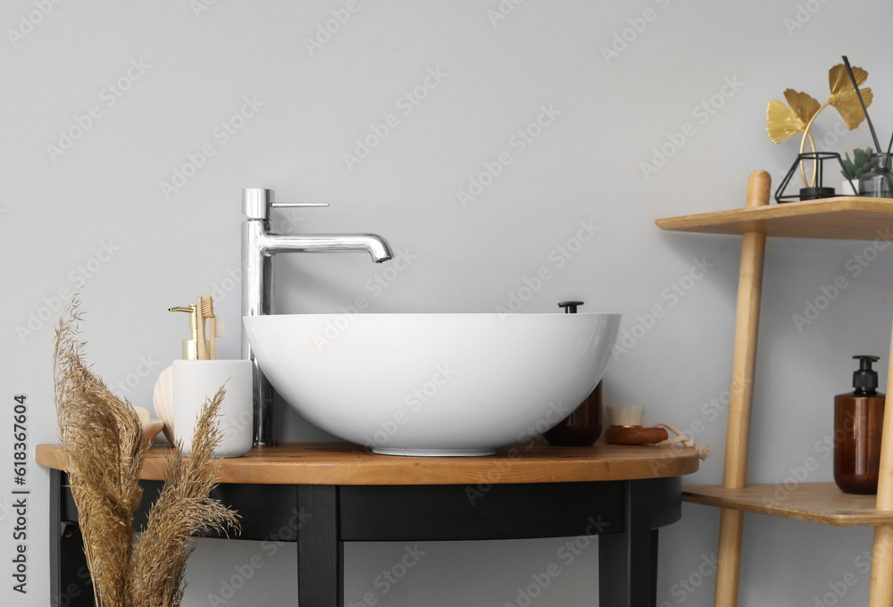 Sink bowl and bath accessories on table in bathroom