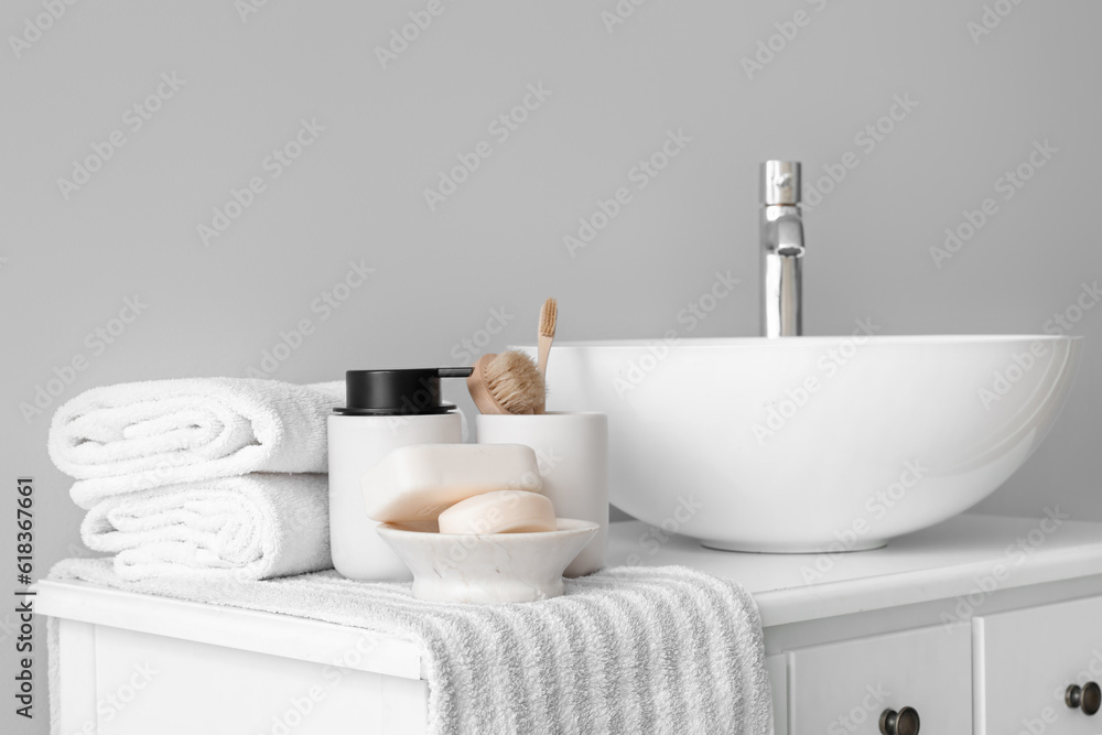 Sink bowl and bath accessories on table in light bathroom