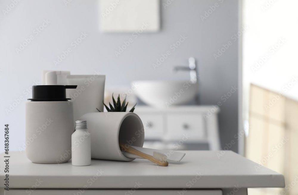 Overturned cup with toothbrush and bath accessories on table in bathroom, closeup