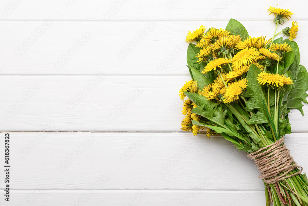 Bouquet of beautiful dandelion flowers on light wooden background