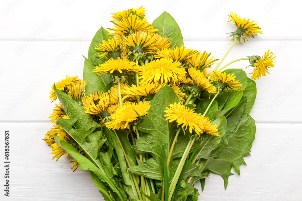 Bouquet of beautiful dandelion flowers on light wooden background, closeup