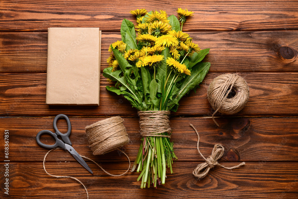 Bouquet of beautiful dandelion flowers, rope, scissors and book on wooden background