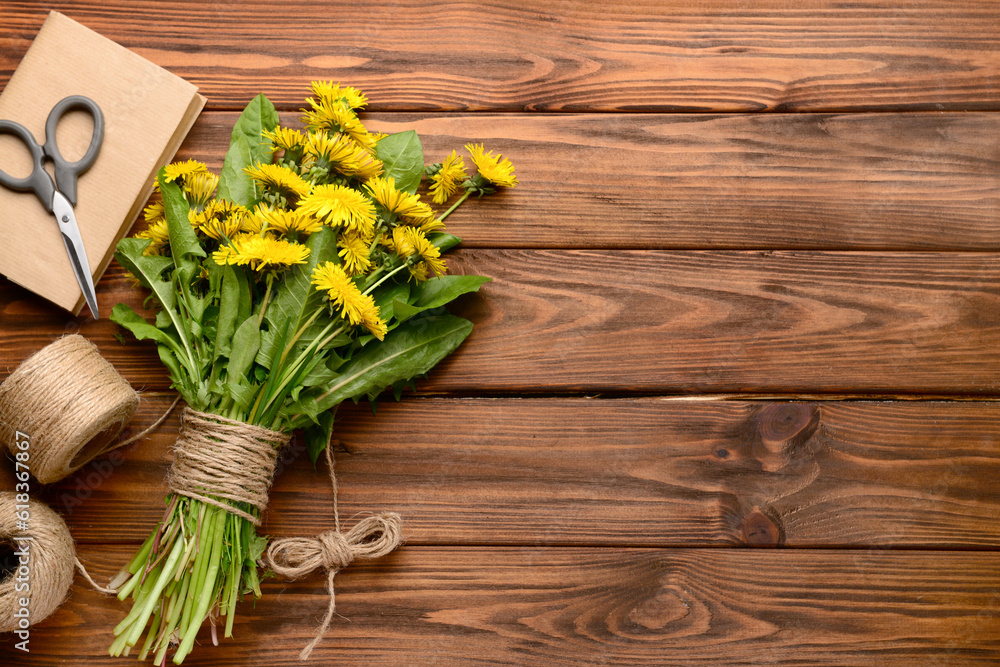 Bouquet of beautiful dandelion flowers, rope, scissors and book on wooden background