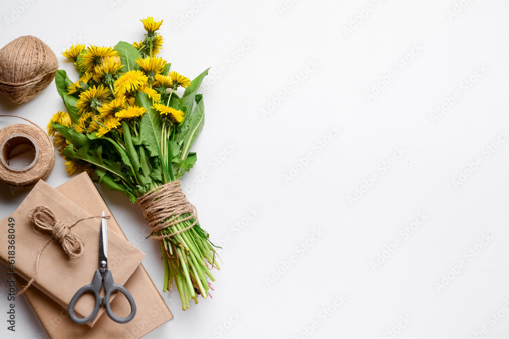 Bouquet of beautiful dandelion flowers, rope, scissors and books on light background