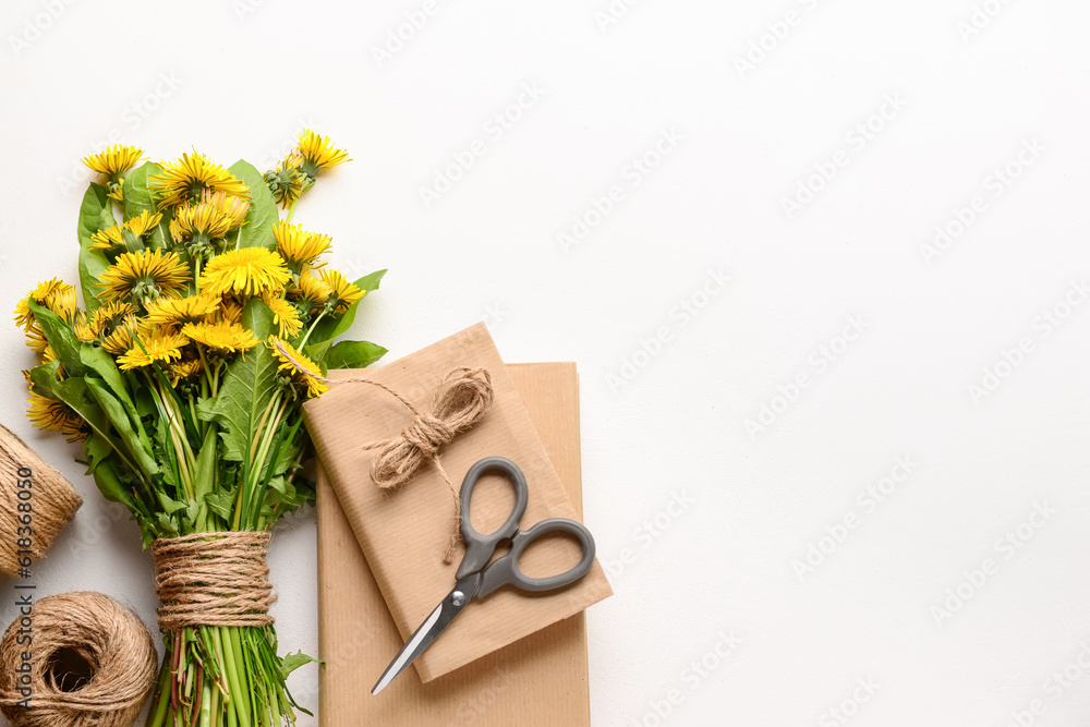 Bouquet of beautiful dandelion flowers, rope, scissors and books on light background