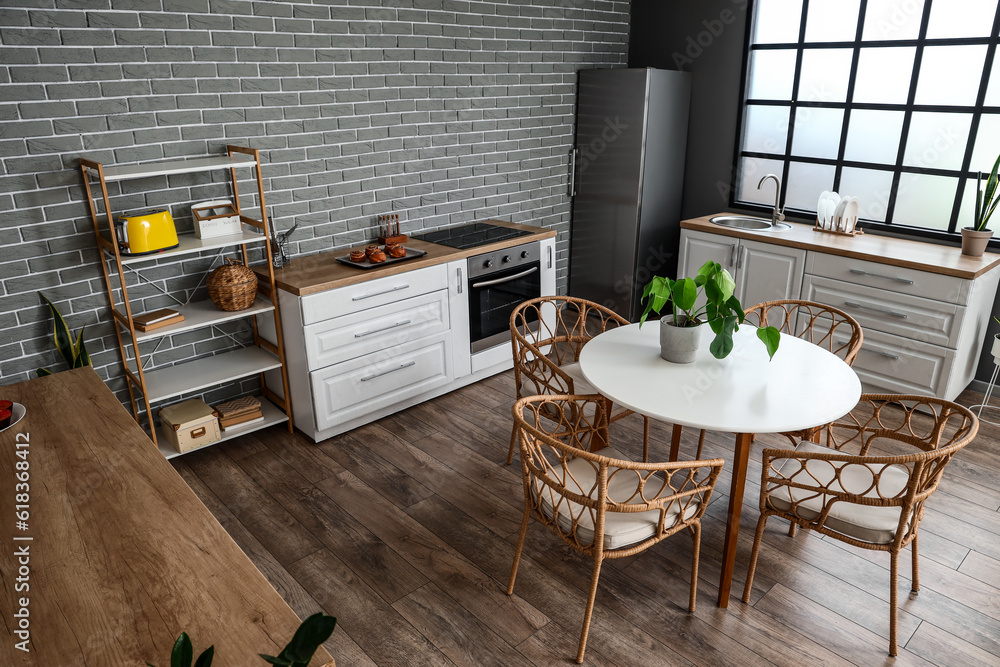 Interior of modern kitchen with dining table, houseplant and kitchen stove