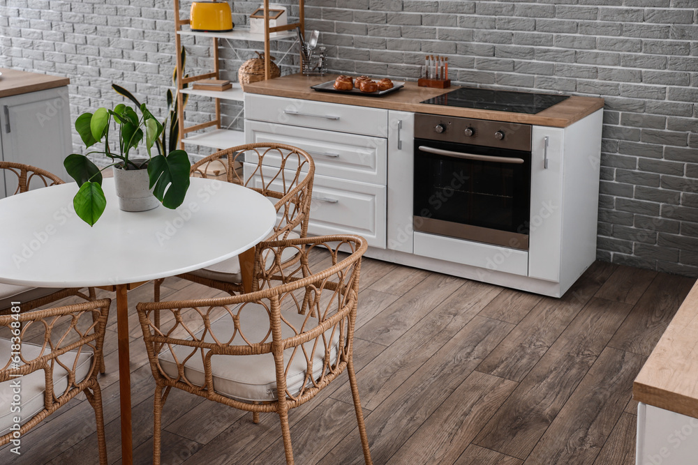 Interior of modern kitchen with dining table, stove, oven and white counters