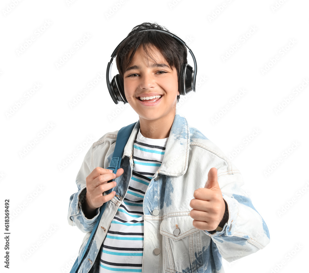 Little boy in headphones with backpack showing thumb-up on white background