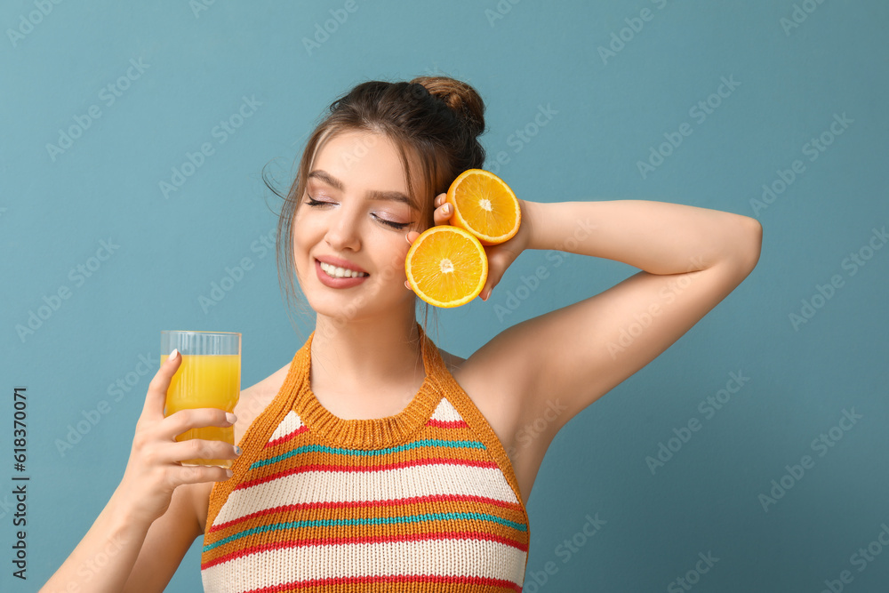 Young woman with glass of juice and oranges on blue background