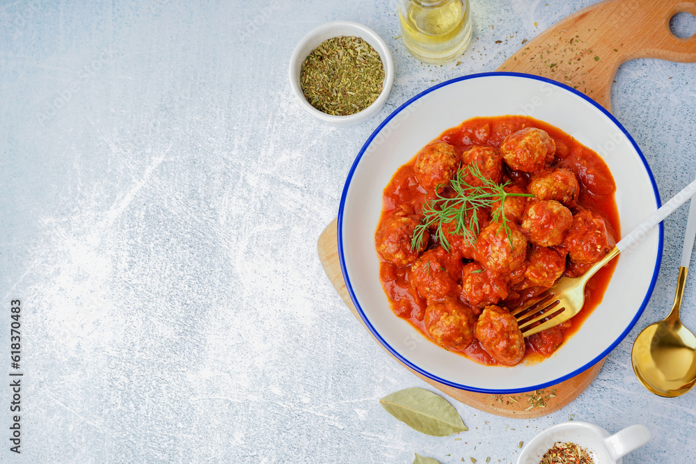 Bowl of tasty meat balls with tomato sauce and dill on blue background