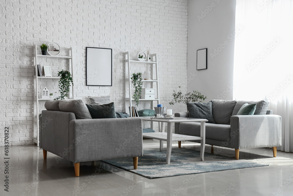 Interior of light living room with cozy grey sofas and coffee table