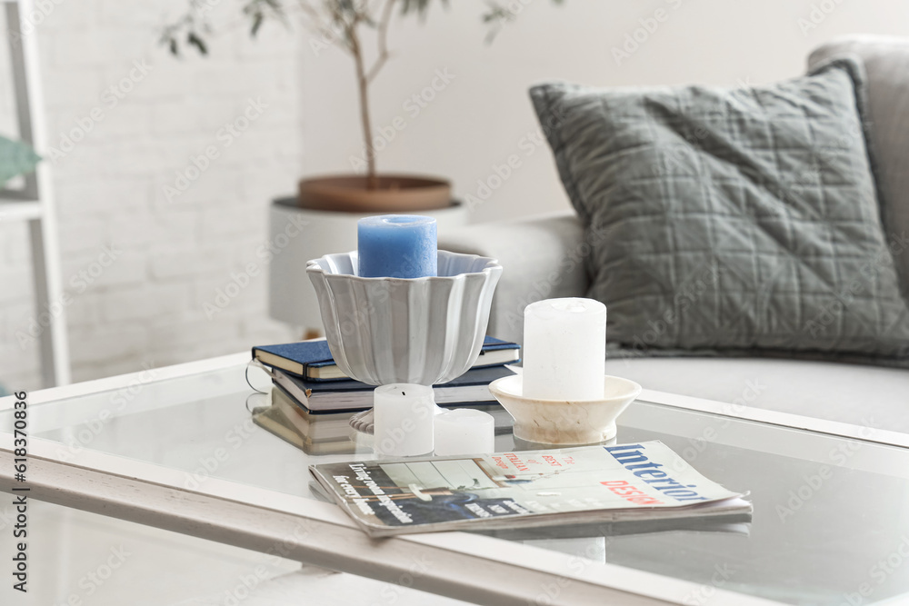 Coffee table with magazines, candles and books in interior of light living room