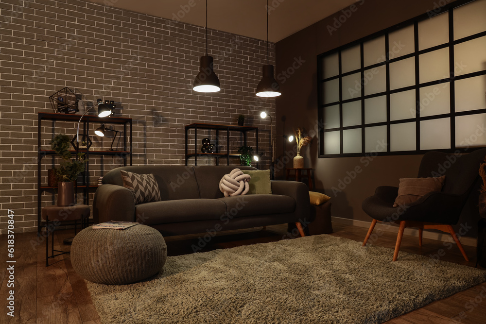 Interior of dark living room with cozy grey sofa and glowing lamps