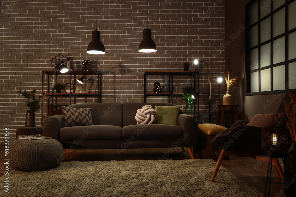 Interior of dark living room with cozy grey sofa and glowing lamps