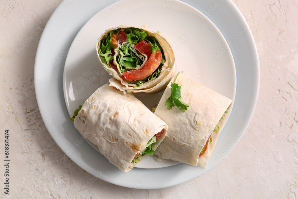 Plates of tasty lavash rolls with tomatoes and greens on light background