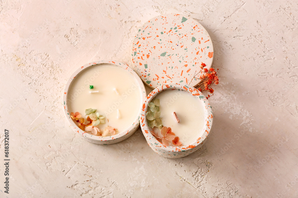 Holders with candles and flowers on white background