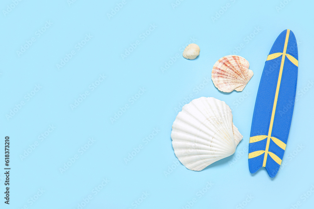 Mini surfboard with seashells on blue background