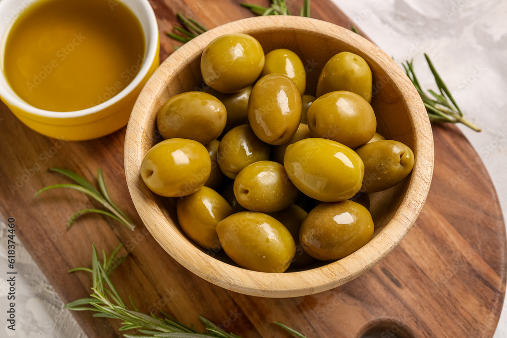 Bowls with ripe olives and oil on light background