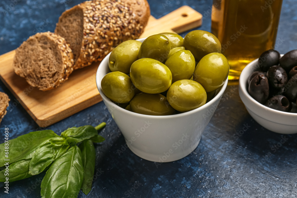 Bowls with ripe olives on blue background