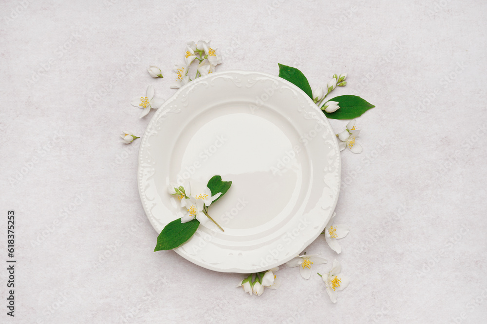 Composition with plate and beautiful jasmine flowers on light background