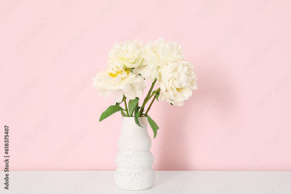 Vase of white peonies on dresser near pink wall