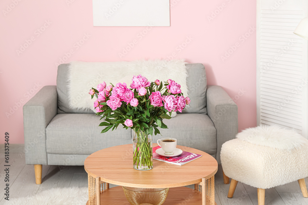 Vase of pink peonies on coffee table with couch in living room