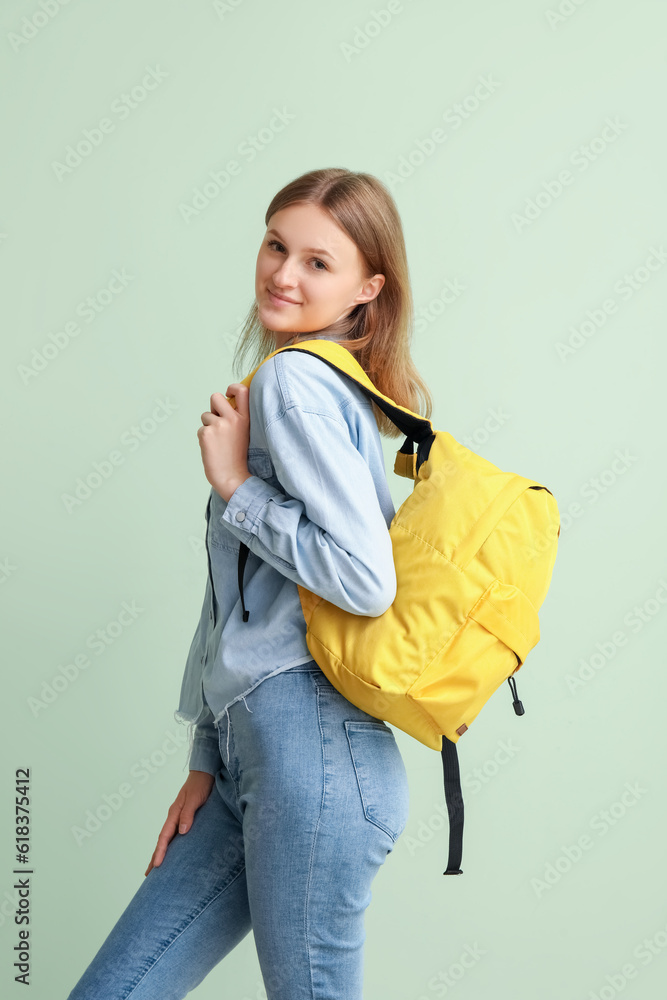 Female student with backpack on green background