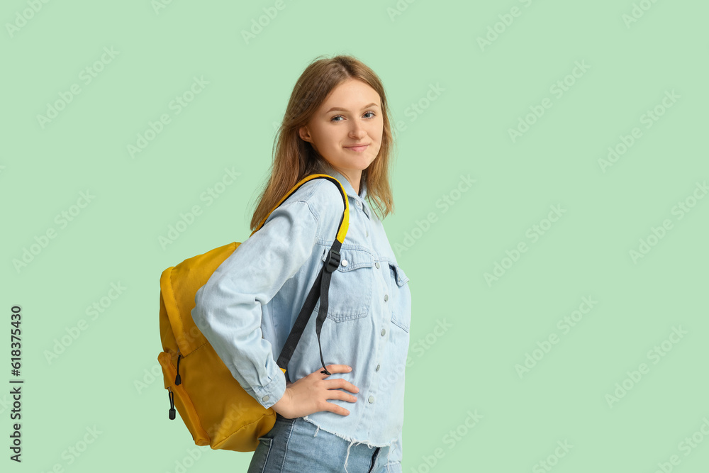 Female student with backpack on green background