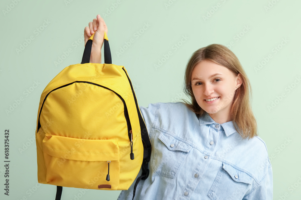 Female student with backpack on green background