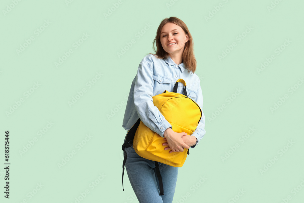 Female student with backpack on green background