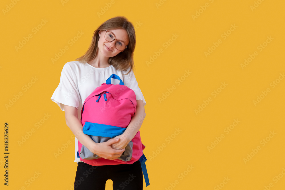 Female student with backpack on yellow background