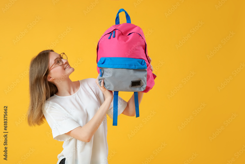 Female student with backpack on yellow background