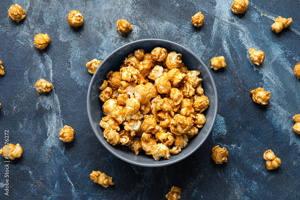 Bowl with tasty popcorn on blue background