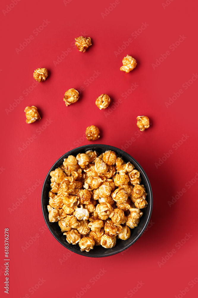 Bowl with tasty popcorn on red background