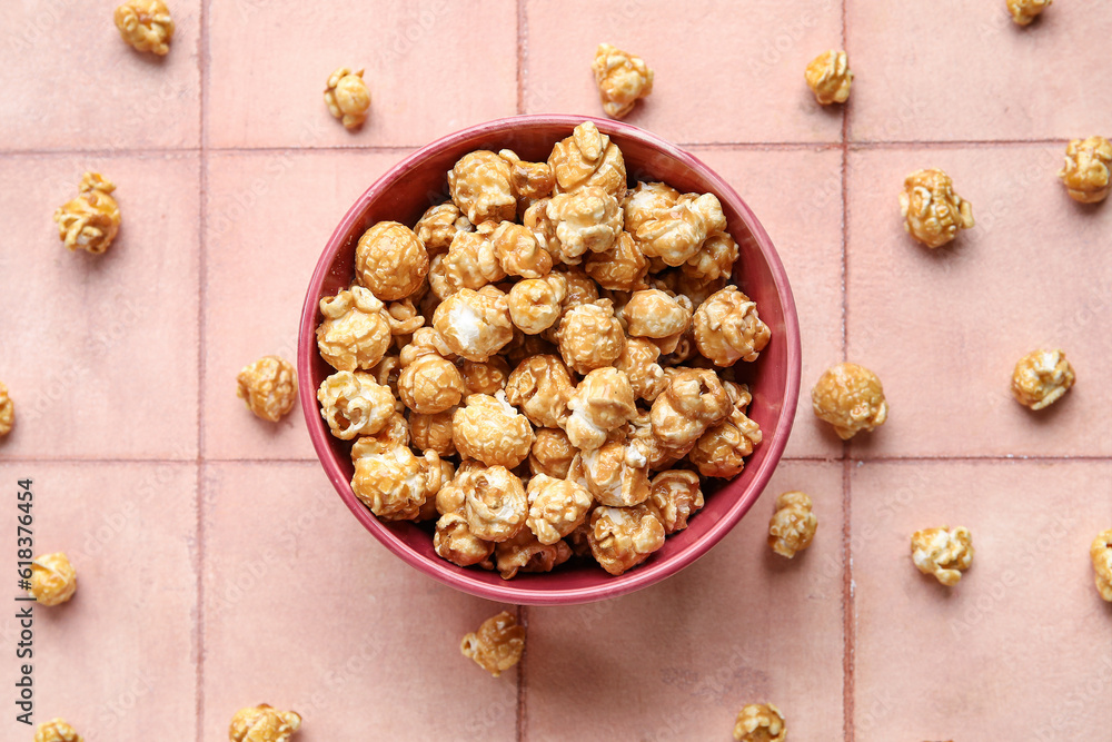 Bowl with tasty popcorn on pink tile background