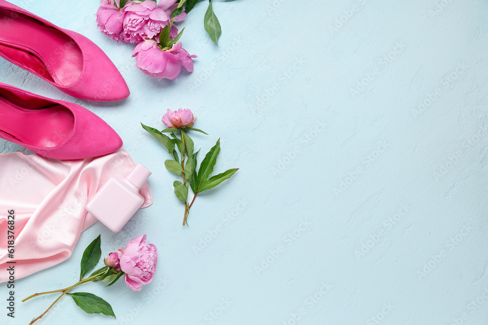 Composition with bottle of perfume, silk scarf, high heels and beautiful peony flowers on light blue