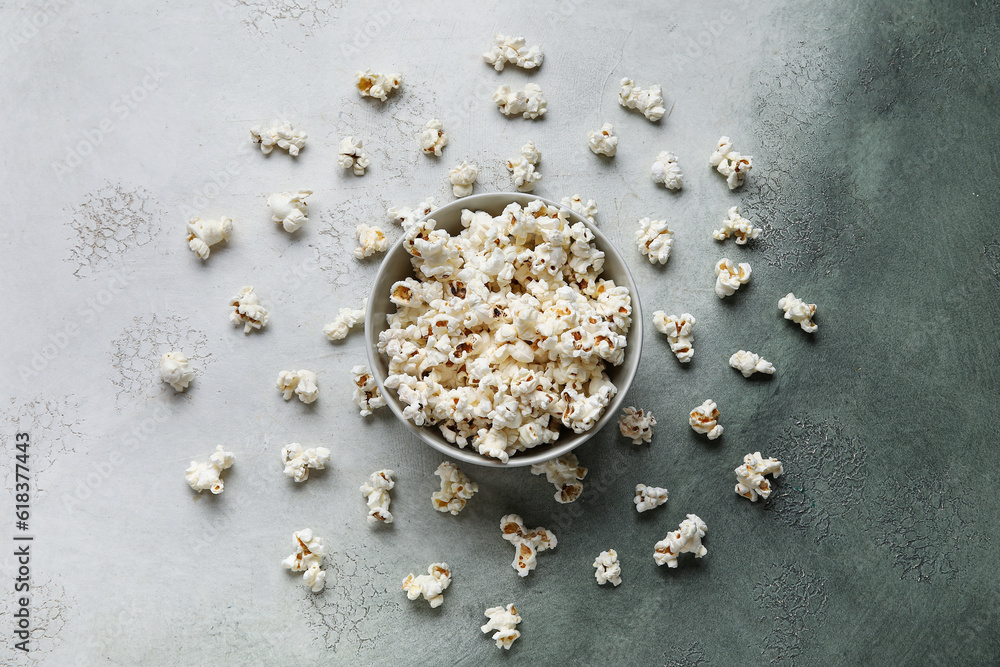 Bowl with tasty popcorn on grey background