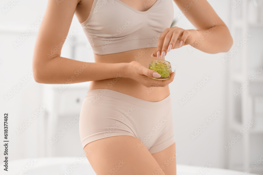 Young woman with anti-cellulite scrub in bathroom, closeup