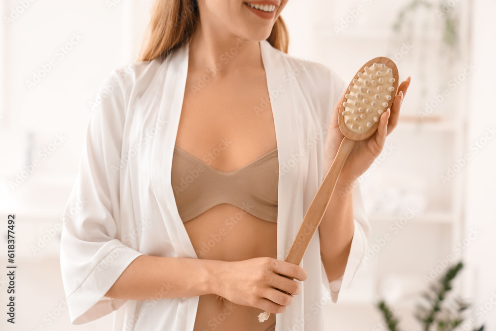 Young woman with anti-cellulite brush in bathroom, closeup