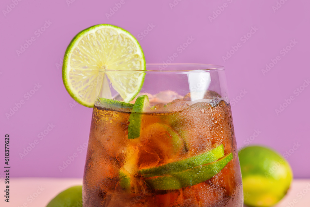 Glass of cold Cuba Libre cocktail on color background