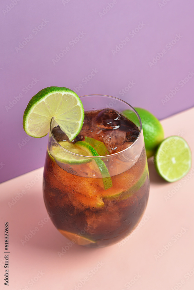 Glass of cold Cuba Libre cocktail on color background